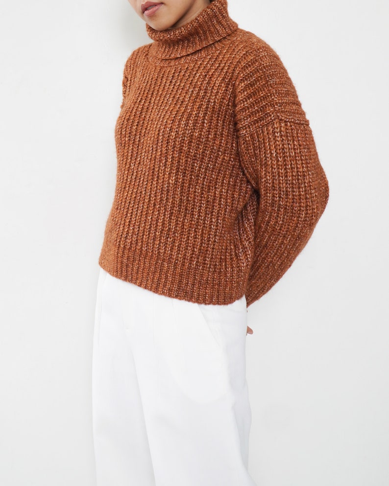 May include: A brown turtleneck sweater with a chunky knit texture.