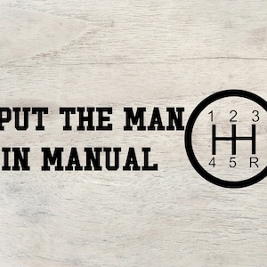 May include: Black text on a light wood grain background reads "I PUT THE MAN IN MANUAL" with a black gear shift graphic. The gear shift graphic has numbers 1, 2, 3, 4, 5, and R.