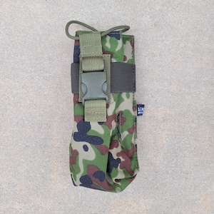 以下が含まれることがあります： 迷彩柄のポーチで、黒いストラップと緑色のバックルが付いています。ポーチには、"LEM."という文字が書かれた小さな青いラベルが付いています。