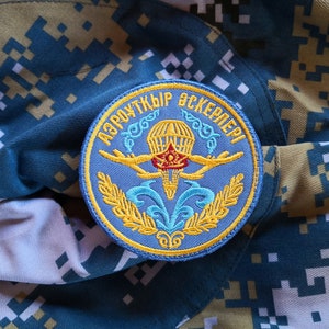 May include: A blue and yellow embroidered patch with the text "АЭРОКУТКИР ЭСКЕРМЕЛЕРИ" in Cyrillic script. The patch features a parachute with a red and yellow design.