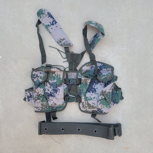 May include: A camouflage tactical vest with multiple pockets and a matching belt. The vest has adjustable straps and buckles.