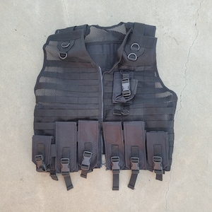 May include: A black tactical vest with multiple pouches and straps. The vest is made of a mesh material and has a zipper closure.