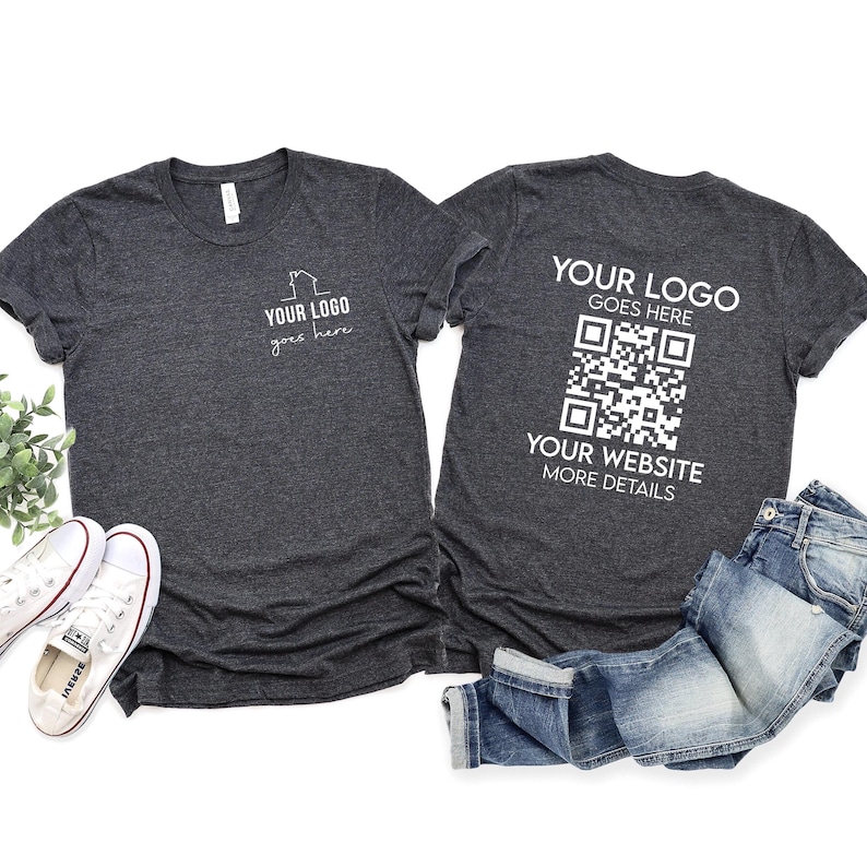 May include: Two dark gray t-shirts with white text. The front of one shirt says "Your Logo goes here". The back of the other shirt says "Your Logo goes here", with a QR code and "Your Website More Details".
