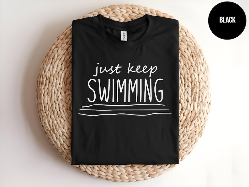 May include: Black t-shirt with white text that reads "just keep swimming" and three white lines underneath.