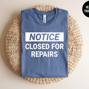 May include: A blue t-shirt with white text that reads "NOTICE CLOSED FOR REPAIRS".