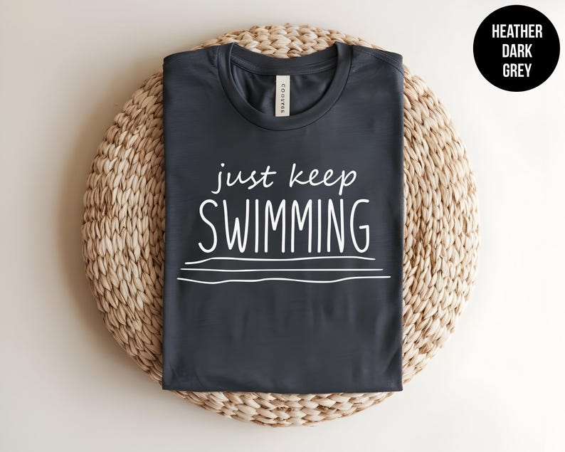 May include: Heather dark grey t-shirt with the text "just keep swimming" in white.