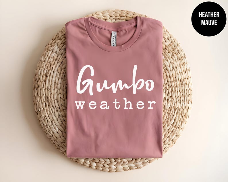 May include: A heather mauve t-shirt with the text "Gumbo weather" printed in white.