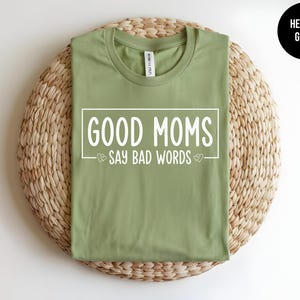 May include: A heather green t-shirt with the text "Good Moms Say Bad Words" printed in white on the front.