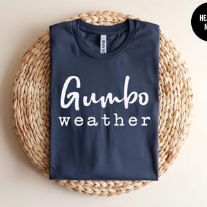May include: A navy blue t-shirt with the text "Gumbo weather" printed in white.