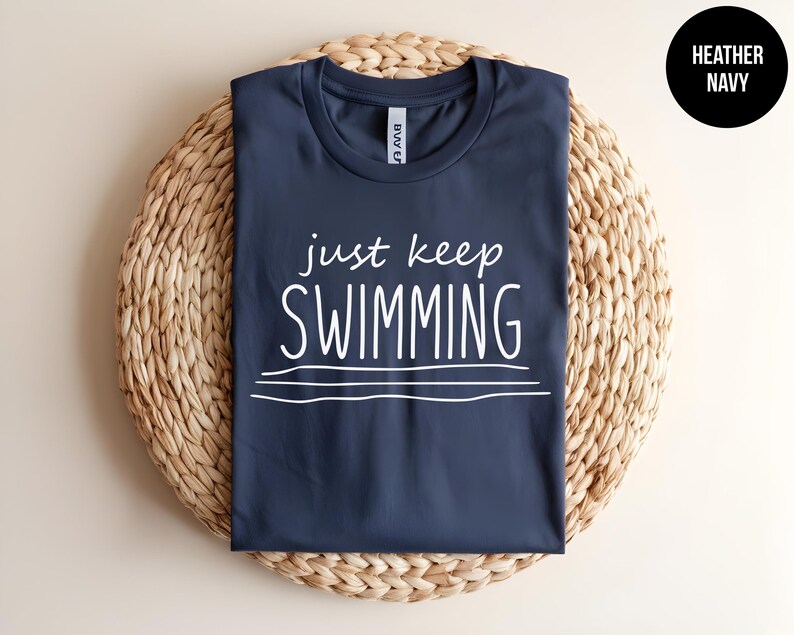 May include: A navy blue t-shirt with the text "just keep swimming" in white lettering.