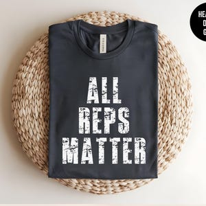 May include: Heather dark grey t-shirt with the text "All Reps Matter" in white distressed lettering.