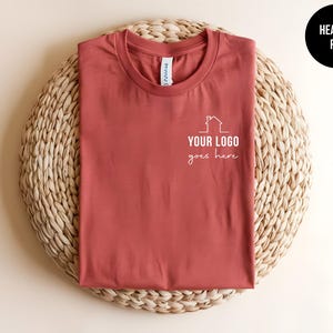 May include: Heather red t-shirt with a white house graphic and the text "YOUR LOGO goes here".