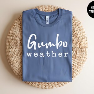 May include: A blue t-shirt with the text "Gumbo weather" in white lettering.