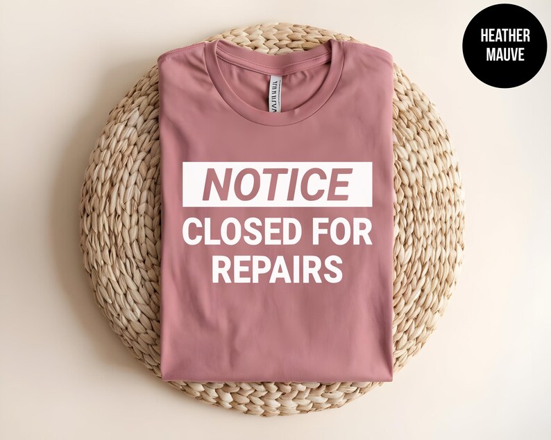 May include: A heather mauve t-shirt with the text "NOTICE CLOSED FOR REPAIRS" in white.