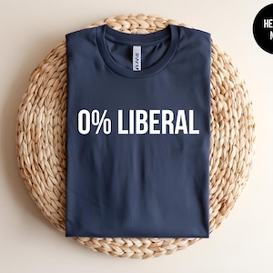 May include: A heather navy blue t-shirt with a crew neckline featuring the text 0% LIBERAL printed in white capital letters across the center of the chest. A small black circular badge in the top right corner displays the text HEATHER NAVY.