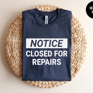 May include: A heather navy blue t-shirt with a white rectangle that says "NOTICE CLOSED FOR REPAIRS".