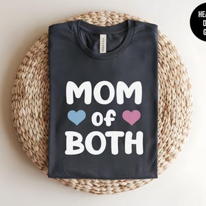 May include: Heather dark grey t-shirt with white text that reads "MOM of BOTH" with a blue heart and a pink heart.