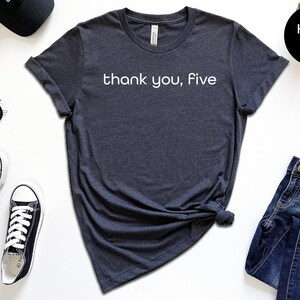 May include: A heather navy blue t-shirt with the text "thank you, five" printed in white on the front.