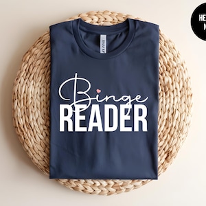 May include: A navy blue t-shirt with the text "Binge Reader" in white with a small pink heart above the word "Binge".