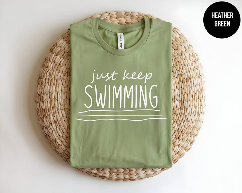 May include: A heather green t-shirt with the text "just keep swimming" in white.