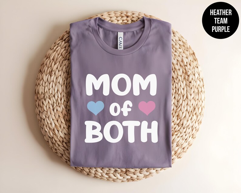 May include: Purple heather t-shirt with the text "MOM of BOTH" in white with a blue and pink heart on either side of the word "of".