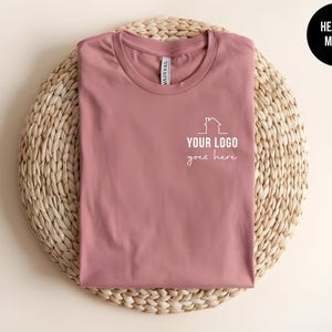 May include: Heather mauve t-shirt with a white outline of a house and the text "YOUR LOGO goes here".