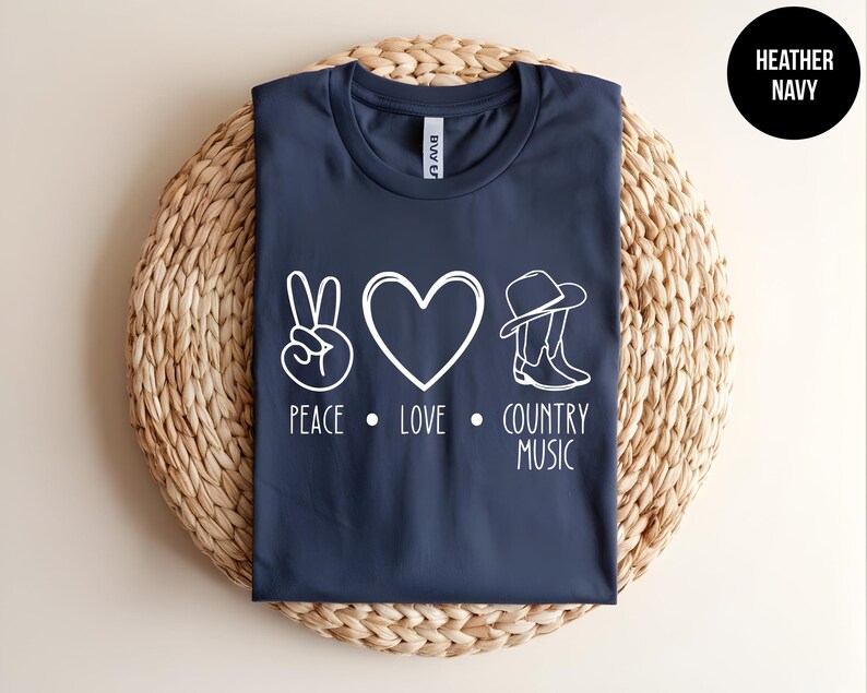 May include: A navy blue t-shirt with a white peace sign, heart, cowboy hat, and boots graphic. The text "Peace. Love. Country Music" is printed below the graphic.