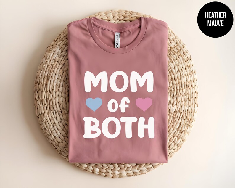 May include: Heather mauve t-shirt with the text "Mom of Both" in white, featuring a blue heart and a pink heart.