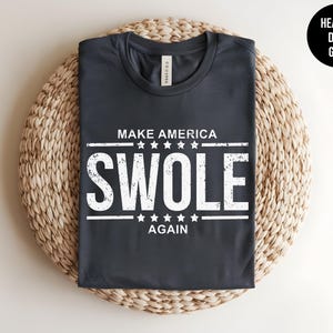 May include: A dark heather grey t-shirt with the text "Make America Swole Again" in white with stars above and below the text.