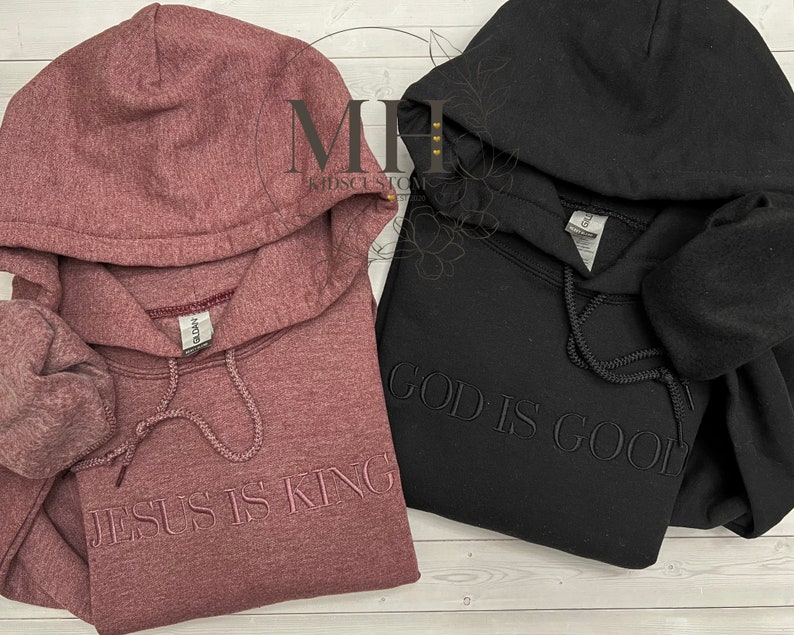 May include: Two hooded sweatshirts, one in a maroon color with the text "JESUS IS KING" and the other in black with the text "GOD IS GOOD".