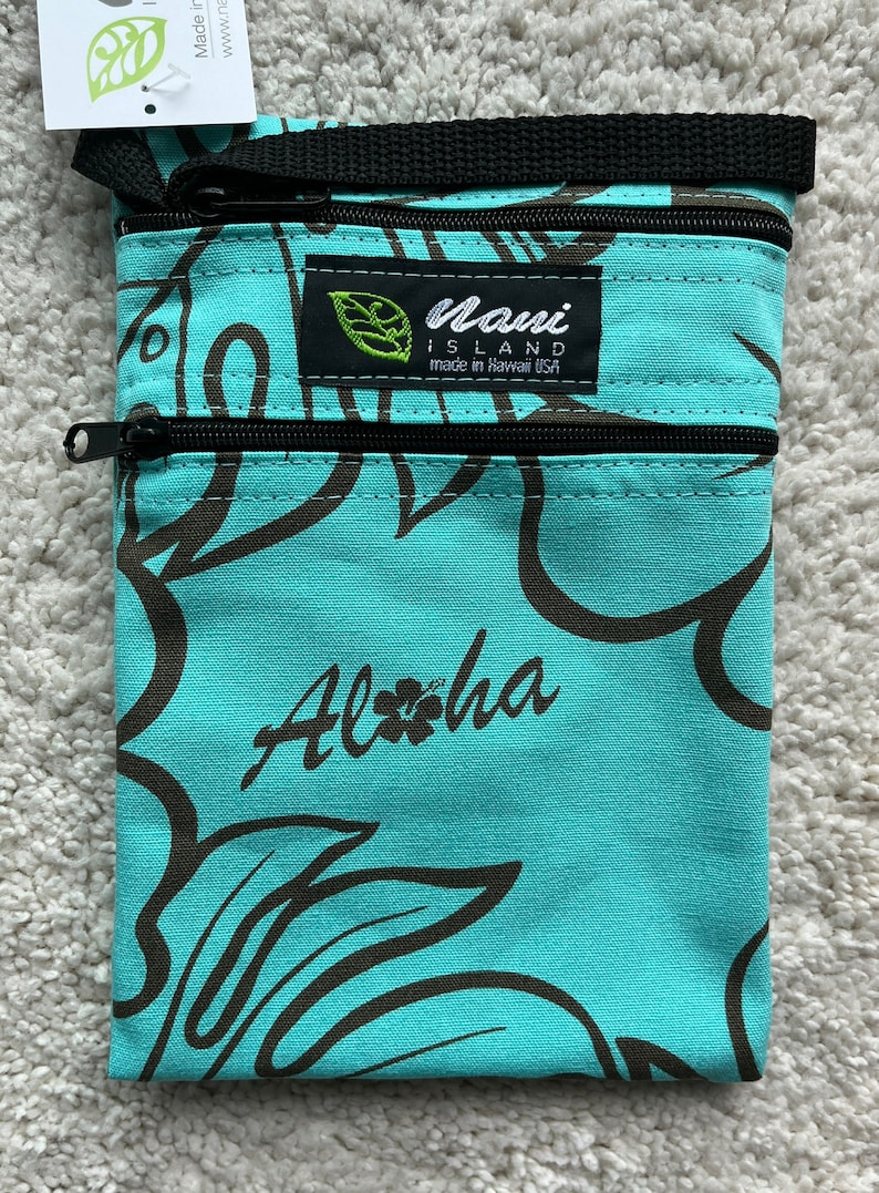 May include: A turquoise fabric pouch with a black zipper closure and a black strap. The pouch features a brown floral pattern and the word "Aloha" in script. The label reads "Maui Island made in Hawaii USA."