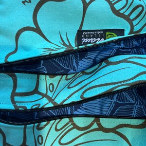 May include: A blue and black patterned tote bag with a zipper closure. The bag has a label that reads "Island Soul! Made in Hawaii, USA".