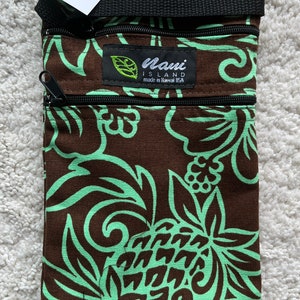 May include: A brown and mint green crossbody bag with a floral pattern. The bag has a black strap and two zippered compartments. The tag reads "Nani Island made in Hawaii USA".