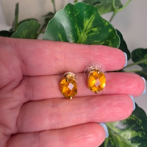 May include: A pair of gold earrings with oval-shaped amber stones.