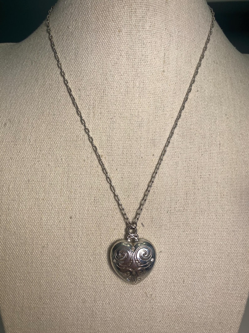 May include: A white ceramic mug with a black handle and the text "But First, Coffee" in a handwritten style. The mug is on a white surface. The mug is approximately 4 inches tall.