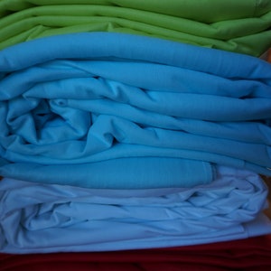 May include: A stack of fabric in four colors: green, blue, white, and red. The fabric is folded neatly and the colors are vibrant.