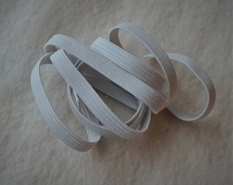 May include: White elastic band, a type of elastic trim, is coiled and ready for use in sewing or crafting projects.