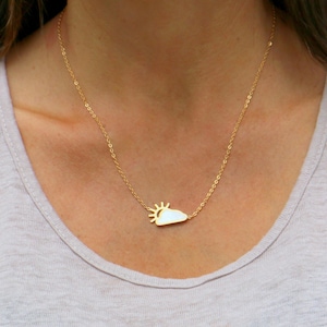 Puede incluir: Un collar dorado con un colgante con un diseño de sol y nube. El colgante es blanco con un sol dorado. El collar se lleva alrededor del cuello.