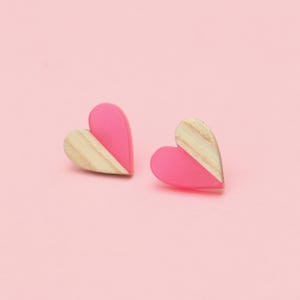 May include: A pair of pink and wood heart-shaped earrings. Each earring is half pink and half wood.