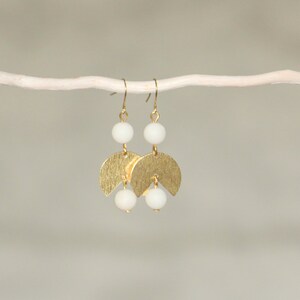 May include: Gold earrings with white beads and a crescent moon design.