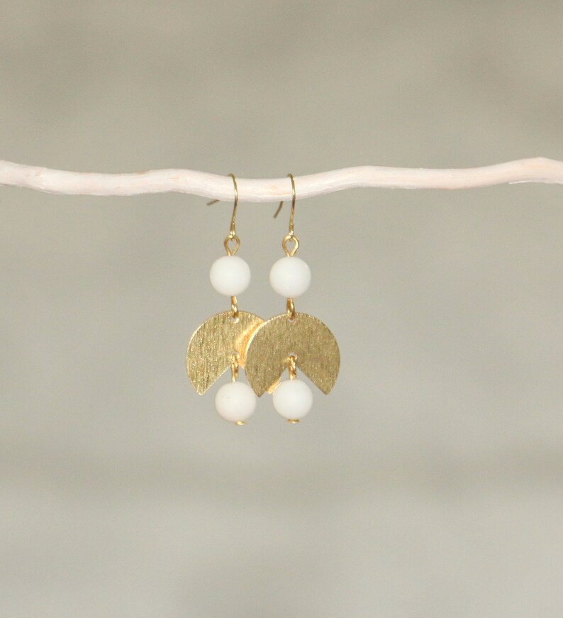 May include: Gold earrings with white beads and a crescent moon design.