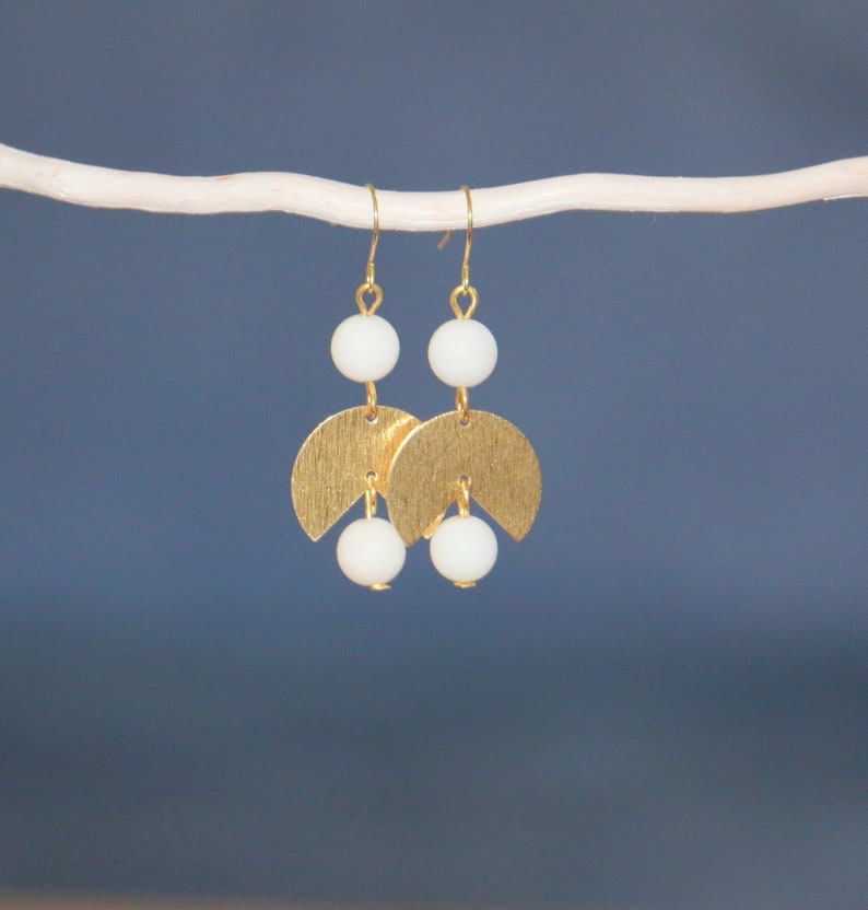 May include: Gold earrings with white beads and a crescent moon design.