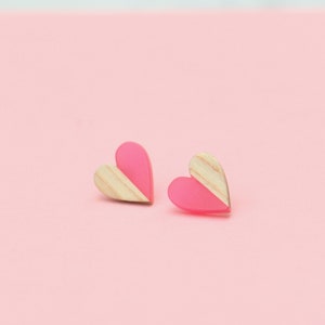 May include: A pair of pink and wood heart-shaped earrings. The earrings are half pink and half wood.