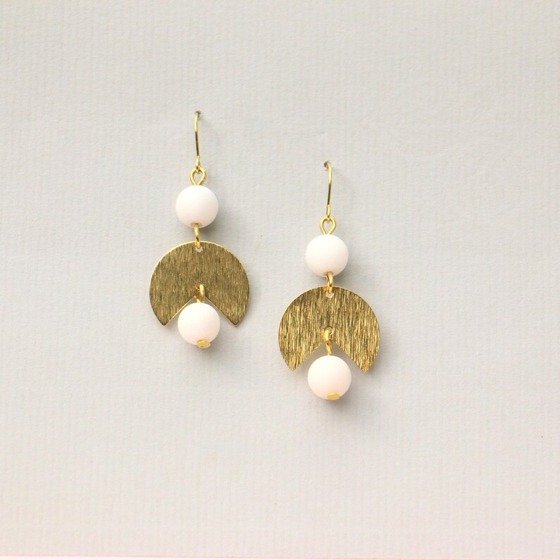 May include: A pair of gold earrings with white beads and a textured, crescent moon design.