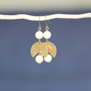 May include: Gold earrings with white beads and crescent moon shapes.