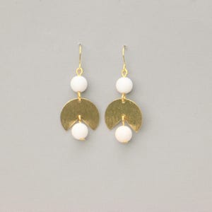 May include: Gold earrings with white beads and a crescent moon shape.