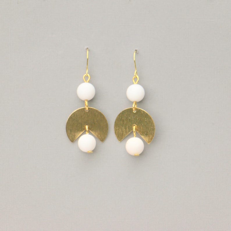 May include: Gold earrings with white beads and a crescent moon shape.