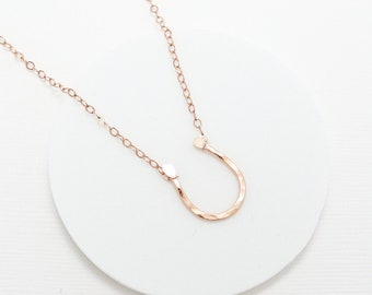May include: A rose gold horseshoe pendant necklace with a delicate chain. The necklace is 16 inches long and has a 3-inch extender chain available for purchase. The horseshoe pendant is approximately 15 mm x 12 mm and 1 mm thick.