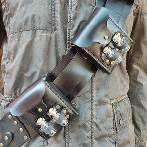May include: A black leather belt with multiple pouches and small glass vials. The belt is worn diagonally across the chest and has a buckle on the left side.