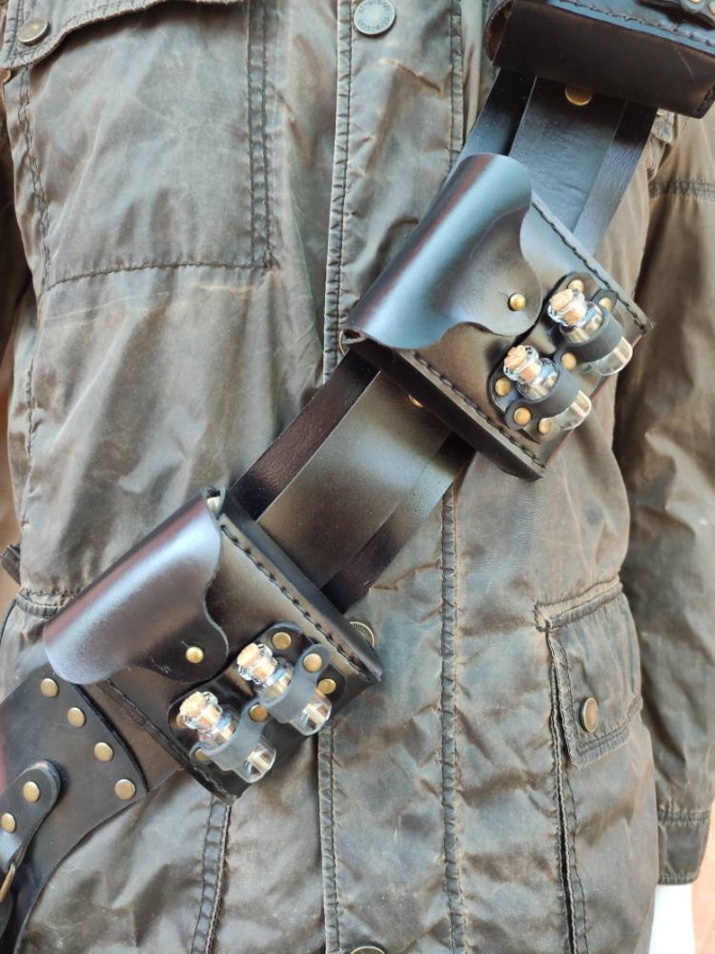 May include: A black leather belt with multiple pouches and small glass vials. The belt is worn diagonally across the chest and has a buckle on the left side.